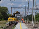 Koparka przy przystanku Zawadzkie, obok przejeżdżający pociąg