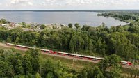 Pociąg jedzie między Wieliszewem a Zegrzem, w tle widać jezioro i las - fot. A.Lewandowski, P.Mieszkowski