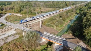 Most nad rzeką Czarna - widać przejazd kolejowo-drogowy i przejeżdżający pociąg